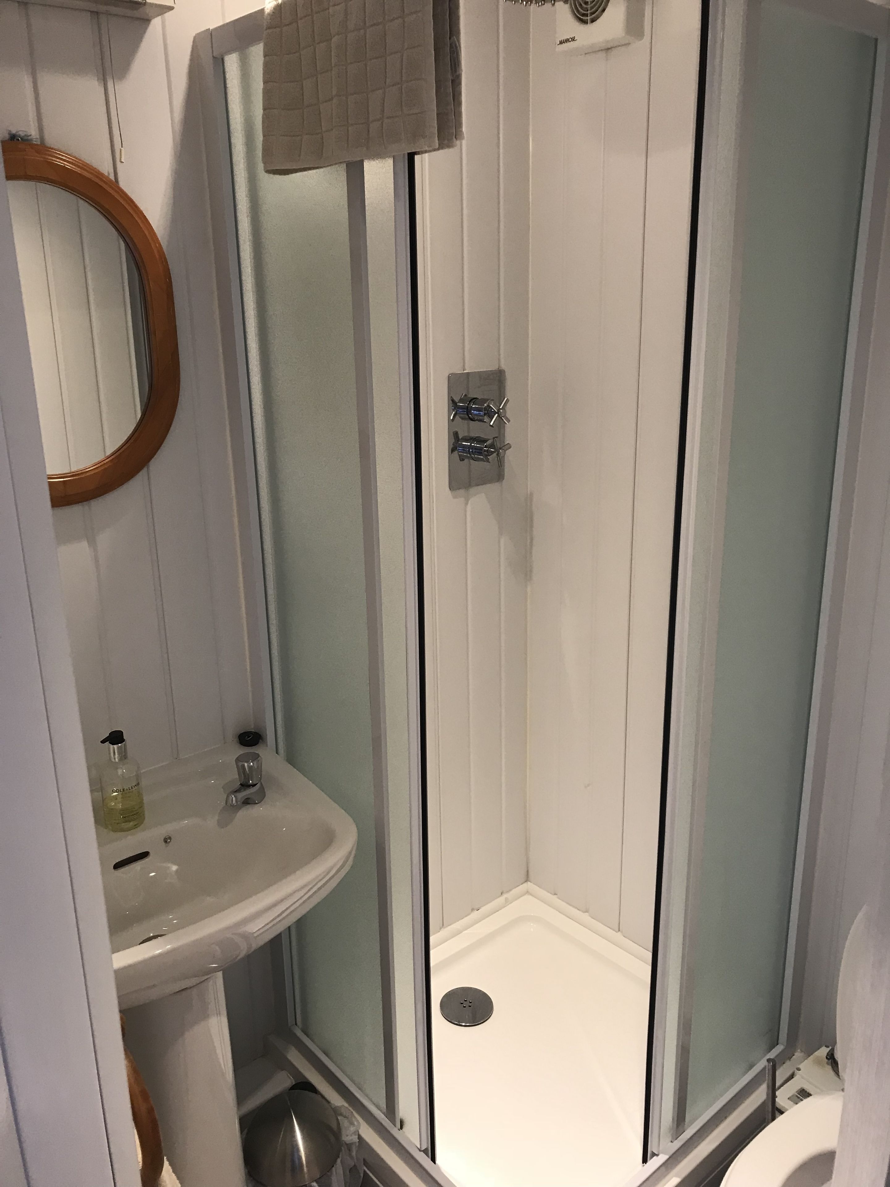 A bathroom with a shower, sink, and mirror.