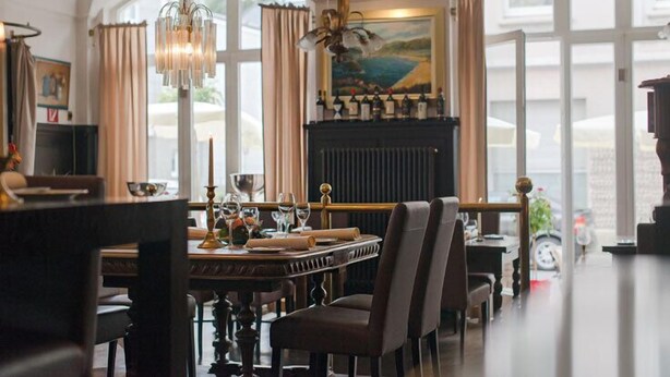 Un espace repas comprenant une longue table, des chaises, un lustre et une cheminée.