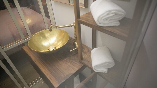 A bathroom with a brass sink, wooden shelves, and a mirror. - Casa Sansera B&B (Chioggia)