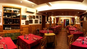 A restaurant with multiple tables set for dining, a bar area with bottles, and framed pictures on the walls. - Casa Sansera B&B (Chioggia)