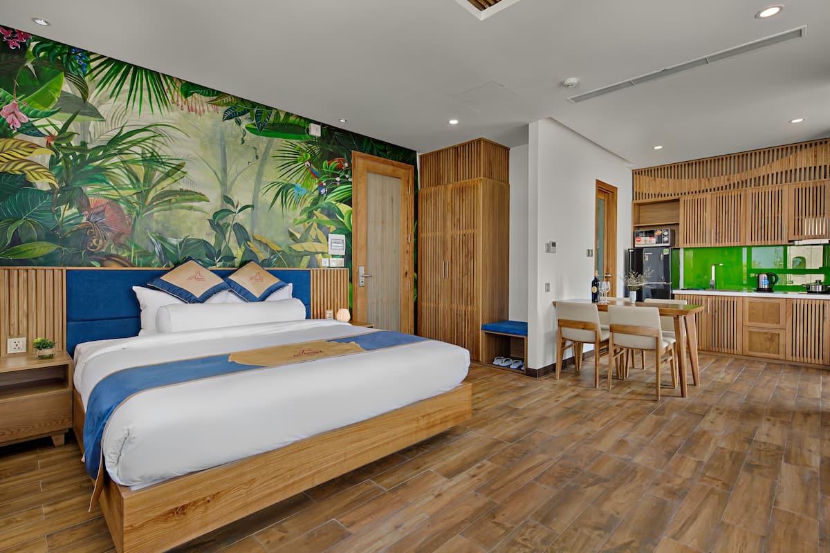A modern room with a bed, a desk, and a kitchenette.