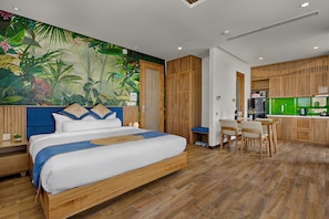 A modern room with a bed, a desk, and a kitchenette.