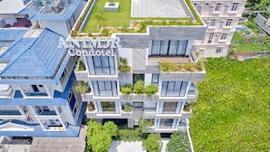 A modern multi-story building with balconies, a rooftop garden, and a sign reading "ANIMDR Condotel". - Animor Green Home Da Nang (Da Nang)