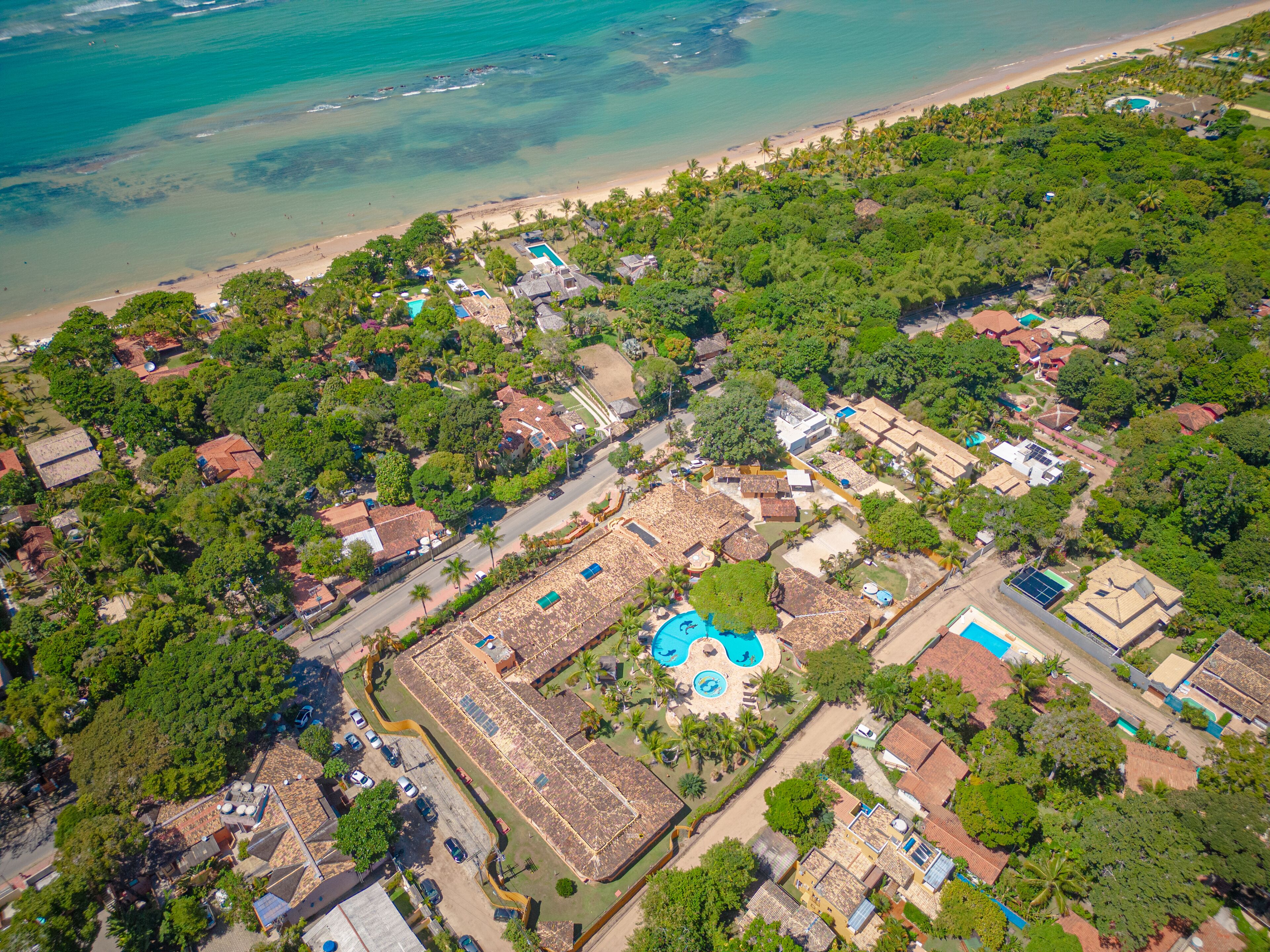 Vista aérea de una zona residencial costera con casas, un complejo de piscinas y una playa.