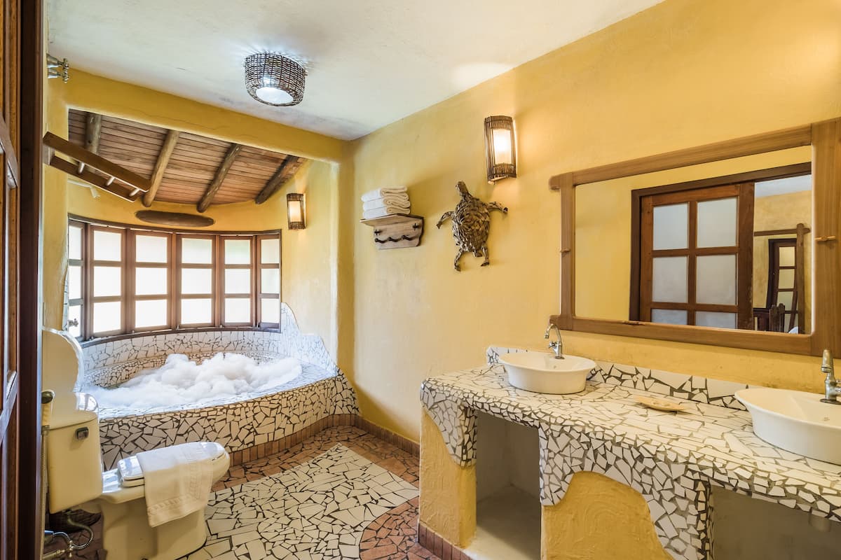 Un bagno con vasca, due lavabi, uno specchio grande e una finestra con vista.