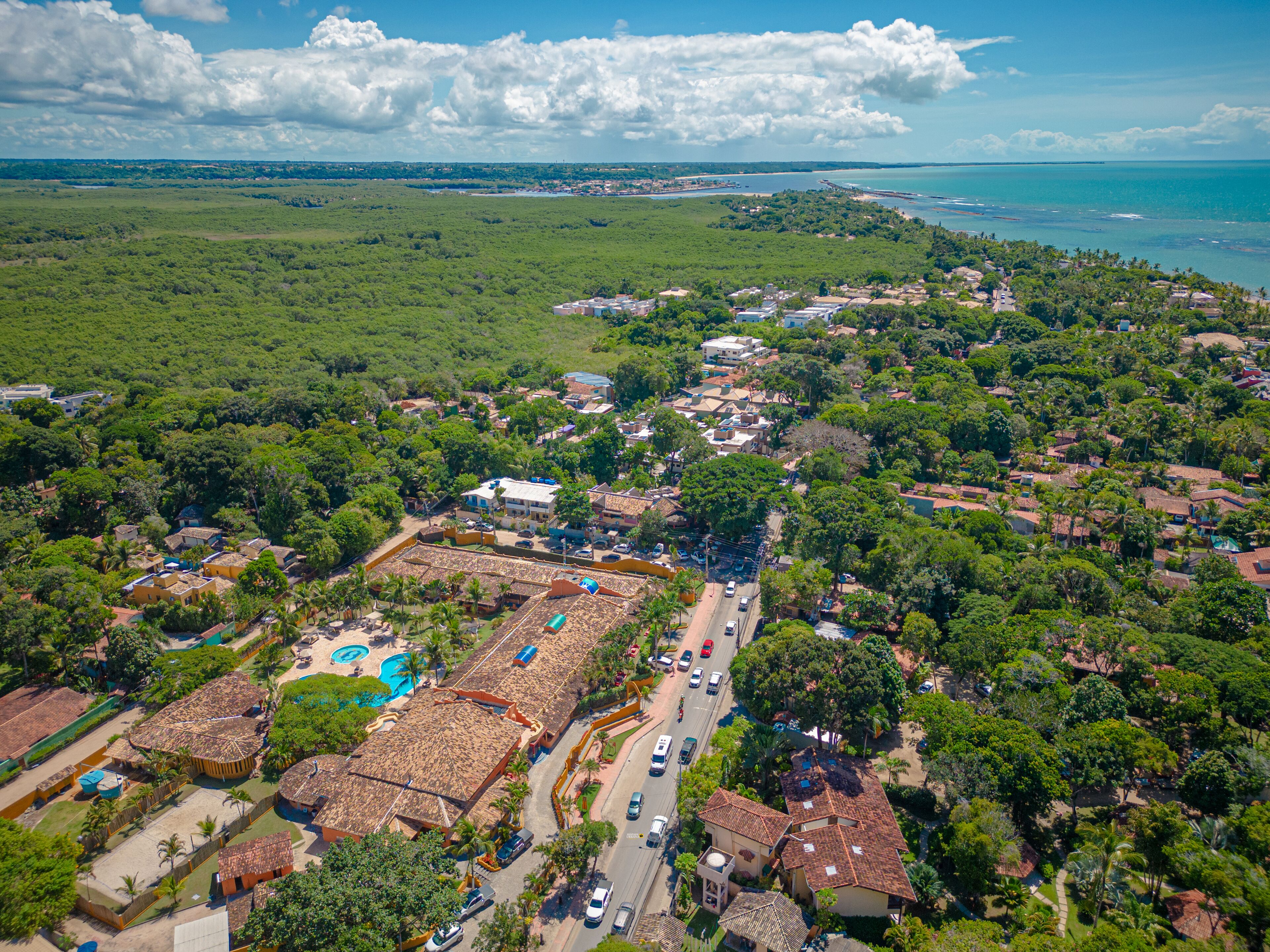 An aerial view of a coastal town with a central square, buildings, and a beach.