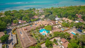 Vista aèria d'una estació turística a la costa, amb diversos edificis, una piscina i una platja.