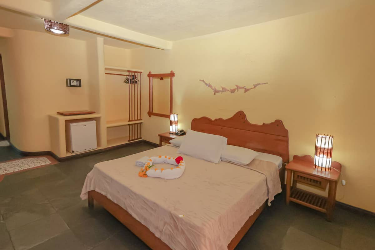 Una camera d'albergo con un letto, comodini, una scrivania con una sedia e un termosifone.