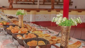 Una taula de buffet amb diversos plats, incloent pa i pastissos, disposats sobre un mantell amb dibuixos florals.