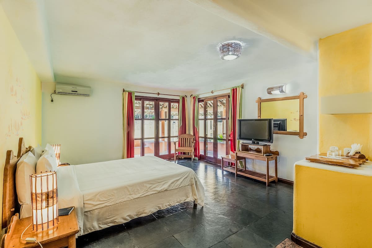 Una camera d'albergo con un letto, una televisione, una scrivania e una finestra con tende.
