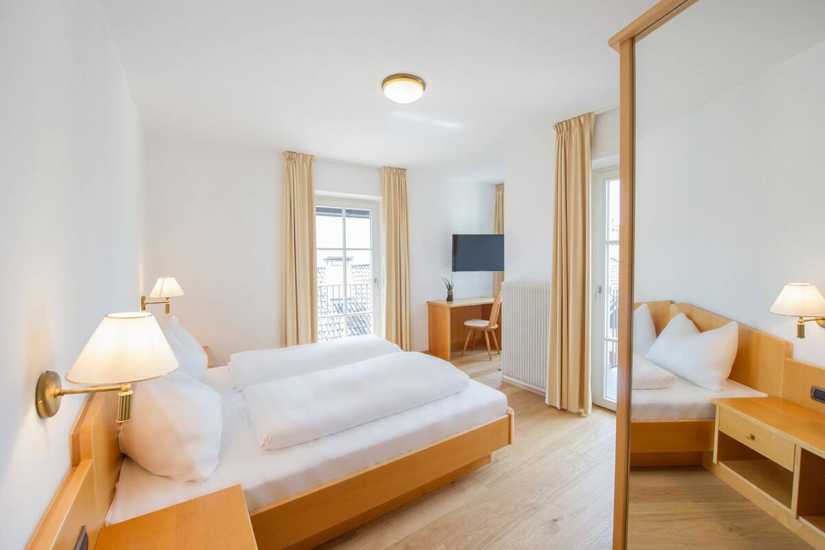 Een hotelkamer met een groot bed, een bureau, een stoel, een televisie en een spiegel.