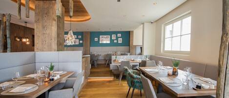 A modern restaurant with wooden accents, booths, and a view of the city.