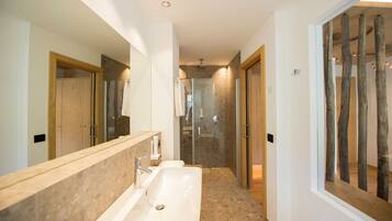 Une salle de bain moderne avec un grand miroir, deux lavabos et une douche à parois de verre.