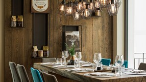 Een houten eettafel met stoelen, een potplant en een hanglamp.