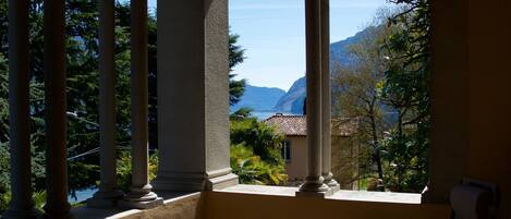 Un balcón con piso a cuadros, una silla y vistas a montañas y árboles.