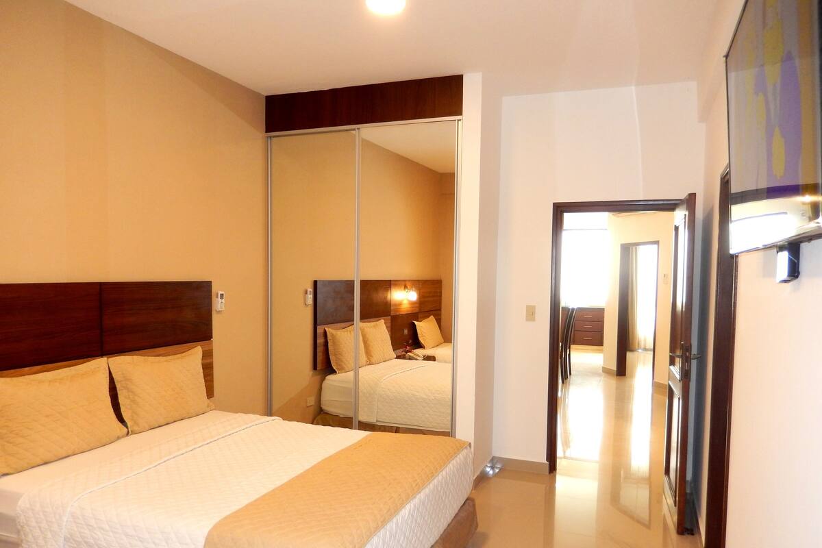 Une chambre d’hôtel avec un grand lit, une armoire et un miroir.