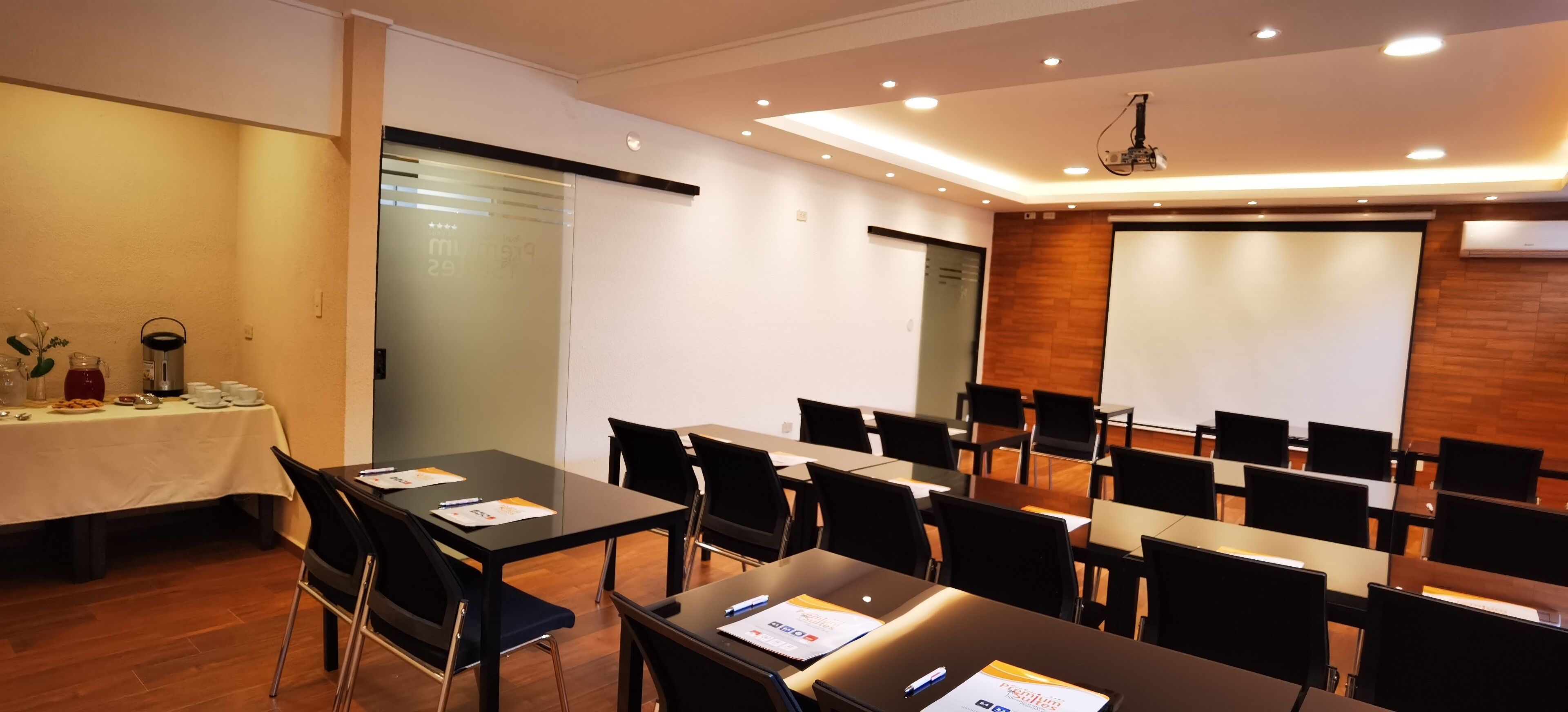 Ein Konferenzraum mit Tischen, Stühlen, einer Projektionsleinwand und einem Präsentationsbereich.