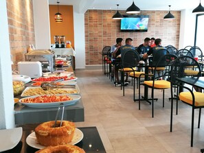 Un área de bufé con diversas opciones de comida y un televisor en la pared.
