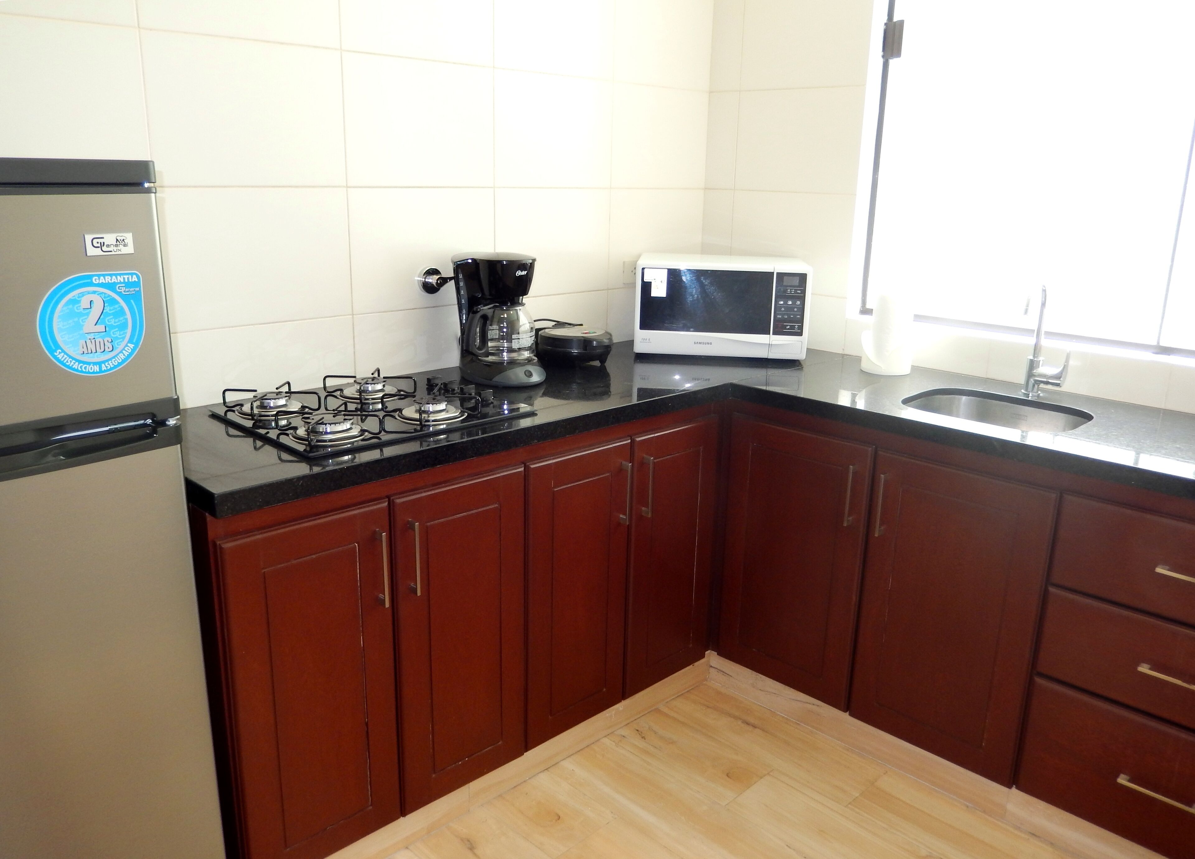 A kitchen with a gas stove, a coffee maker, a microwave, and wooden cabinets.