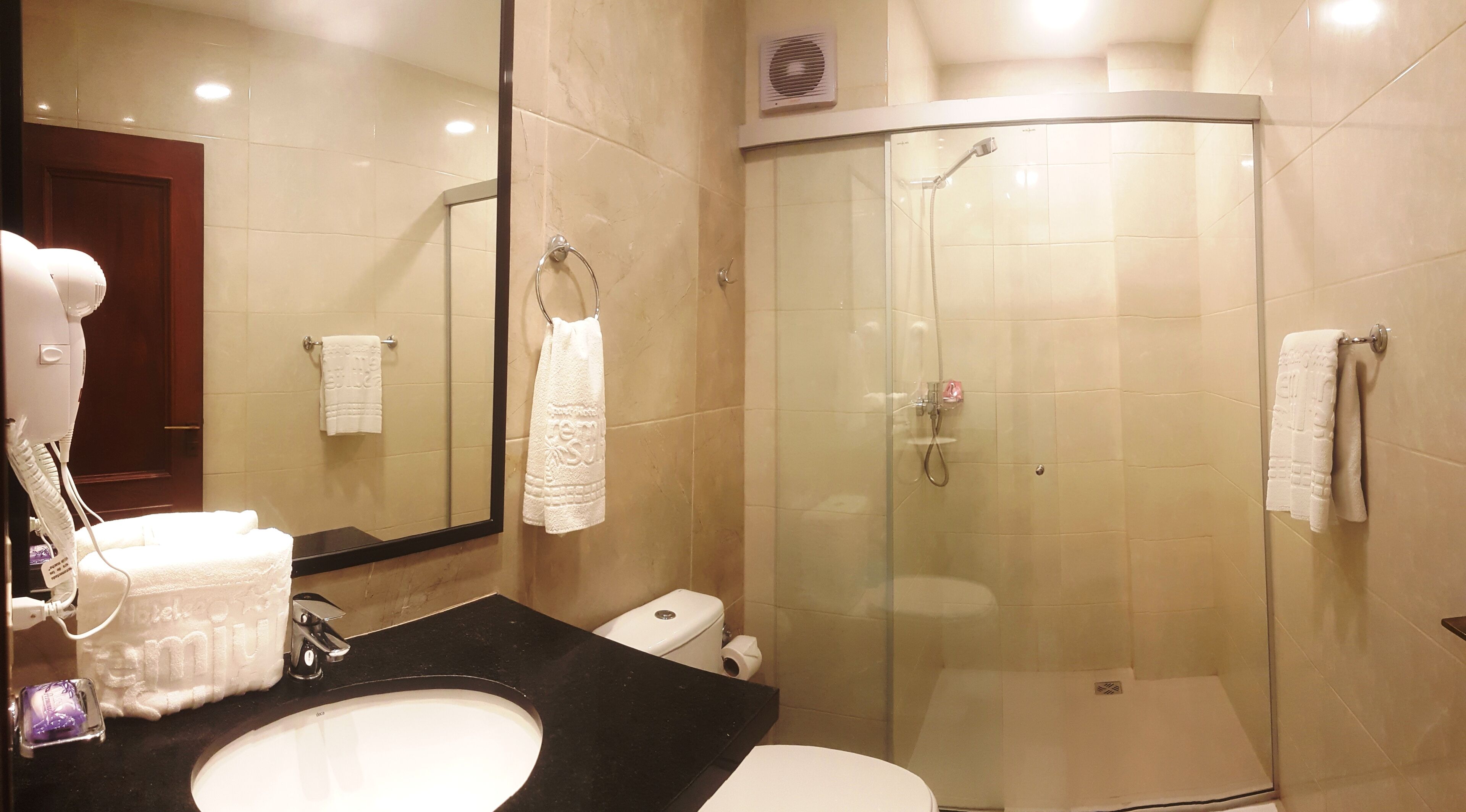 A modern bathroom with a glass-enclosed shower, a sink with a black countertop, and a mirror above the sink.