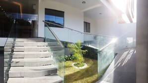 A modern staircase with glass railings, leading to a landing with a small garden area.