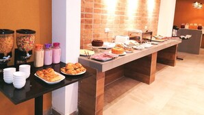 A buffet setup with various food items, including pastries, a cake, and beverages.