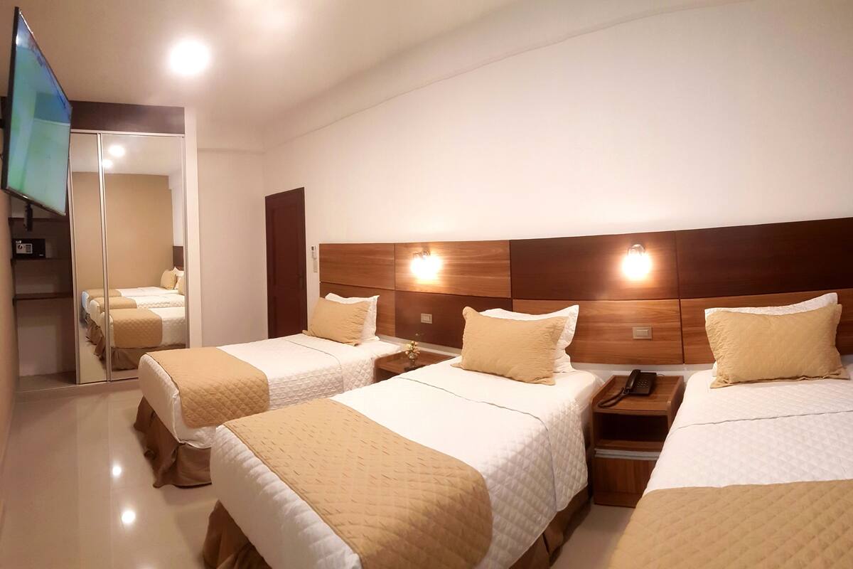 Une chambre d’hôtel avec deux lits, une tête de lit en bois, des tables de chevet avec des lampes et un miroir.