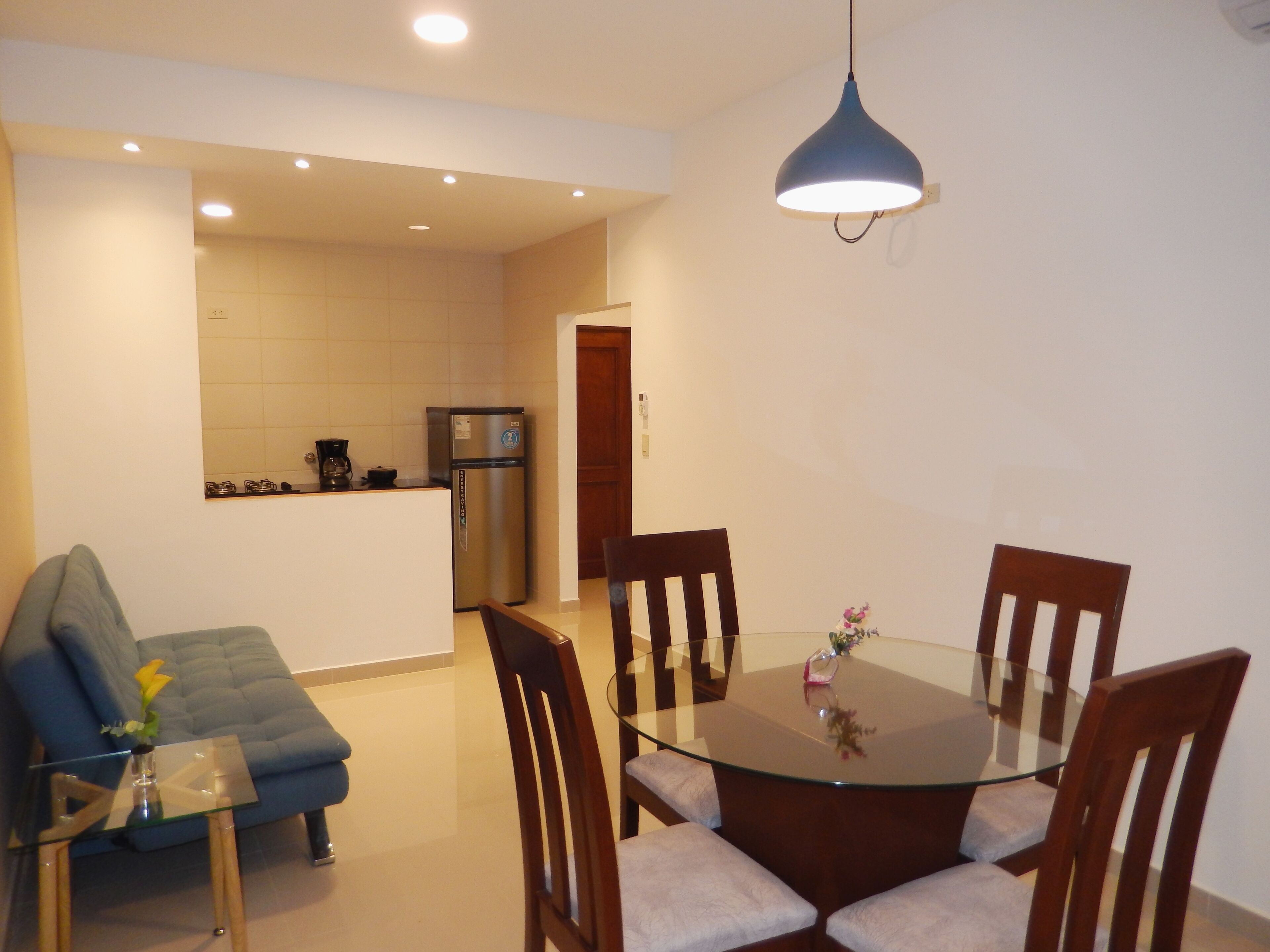 Una cucina moderna con frigorifero, un tavolo da pranzo con sedie e una lampada a sospensione blu.