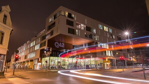 Moderni hotelli, jossa on useita kerroksia, suuret ikkunat ja selkeästi näkyvä «Q42»-kyltti.