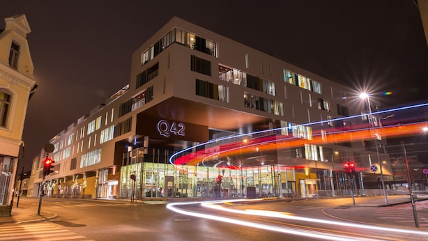 Un hôtel moderne à plusieurs étages, doté de grandes fenêtres et d’une enseigne bien visible indiquant « Q42 ».
