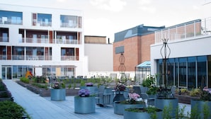 Une cour intérieure urbaine moderne, agrémentée de plantes en pot, de sièges extérieurs et, en arrière-plan, de bâtiments contemporains.