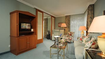 A living room with a sofa, a coffee table, a television on a wooden cabinet, and a lamp.