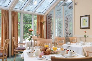 Un ambiente para desayunar con mesas, sillas y alimentos para el desayuno.