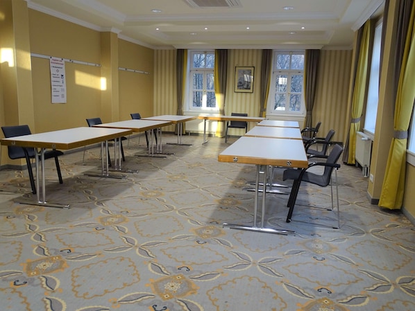 A conference room with tables and chairs, a bulletin board with a sign, and windows with curtains. - Hotel Am Schlosspark (Gotha)