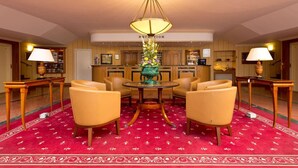 A hotel reception area with a round table, four chairs, a chandelier, and a red carpet. - Hotel Am Schlosspark (Gotha)