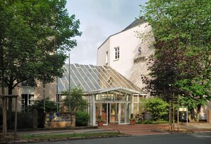Un hotel con entrada de vidrio, un letrero que dice "Hotel & Restaurant" y un edificio con un logo en forma de 'S'.