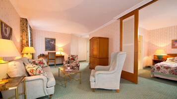 Ein Hotelzimmer mit Sofa, Sessel, Esstisch und Schrank.