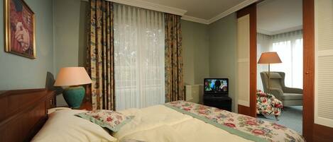 A hotel room with a large bed, two lamps, a television, and a chair.