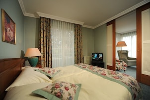 Una habitación de hotel con una cama grande, dos lámparas, un televisor y una silla.