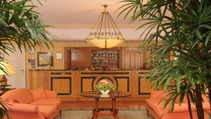 A reception area with a chandelier, two sofas, a table with a vase, and wooden cabinets. - Hotel Am Schlosspark (Gotha)