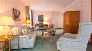 A hotel room with a sofa, armchairs, a desk, and a cabinet. - Hotel Am Schlosspark (Gotha)