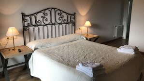 A neatly made bed with a patterned bedspread, two bedside lamps, and a folded towel on the bed.