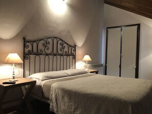 Une chambre à coucher avec un lit, deux tables de chevet avec des lampes, un radiateur et une armoire.