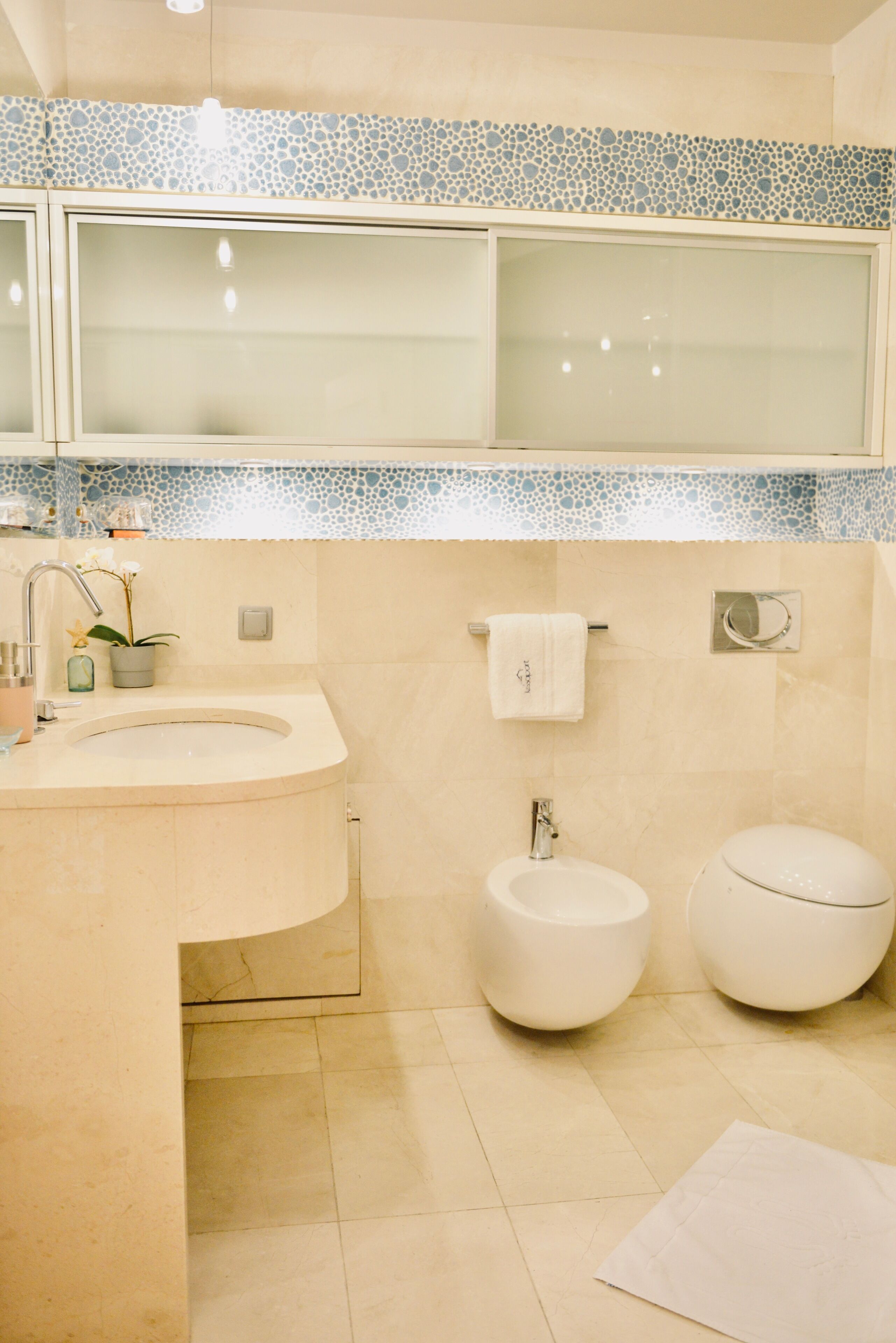 Een badkamer met een wastafel, twee toiletten en een spiegel.