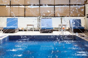 A swimming pool with blue tiles, two lounge chairs, and a covered area with a view of the pool. - Lijam Hotel (Amman)