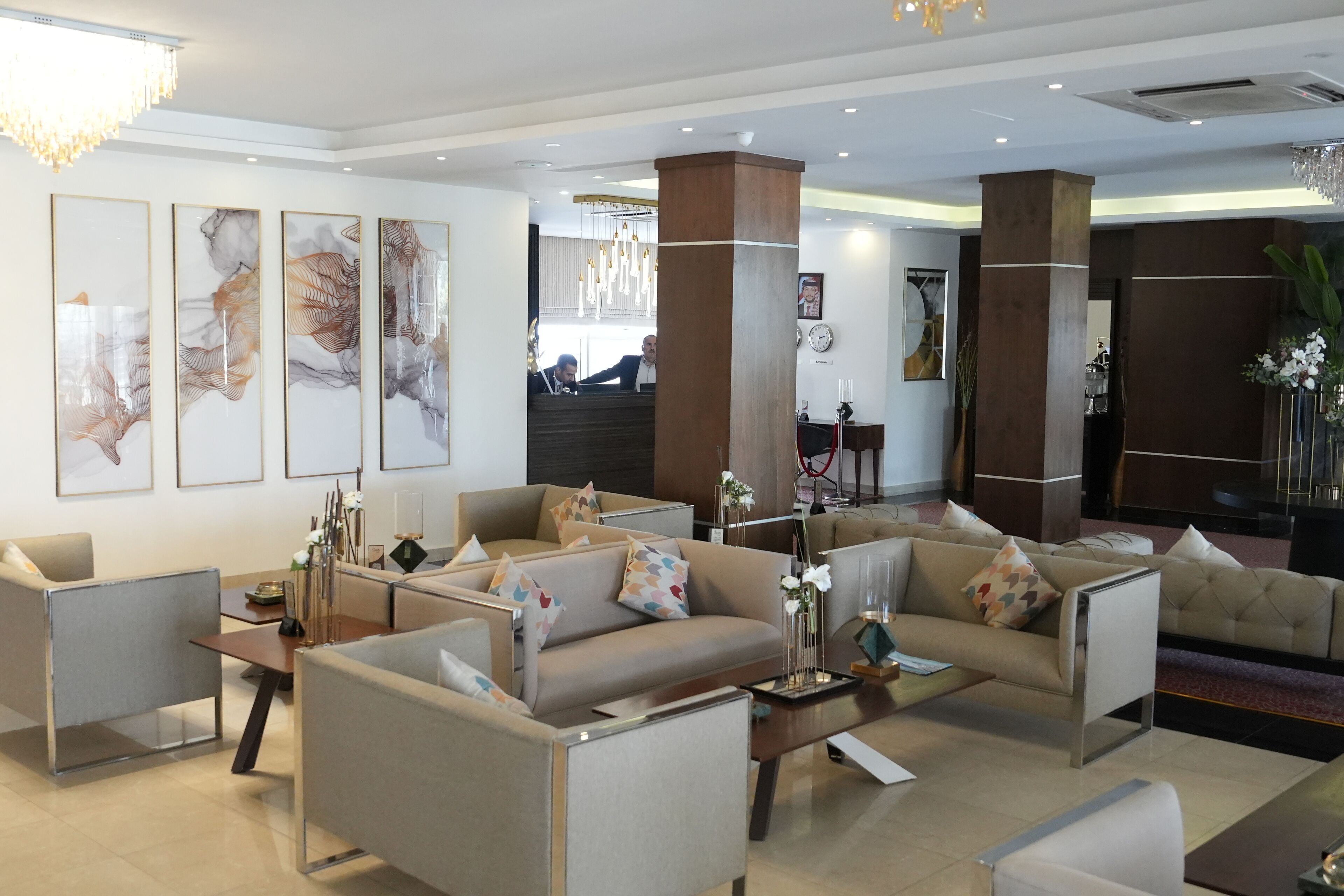 A modern hotel lobby with a seating area, artwork on the walls, and a reception desk.
