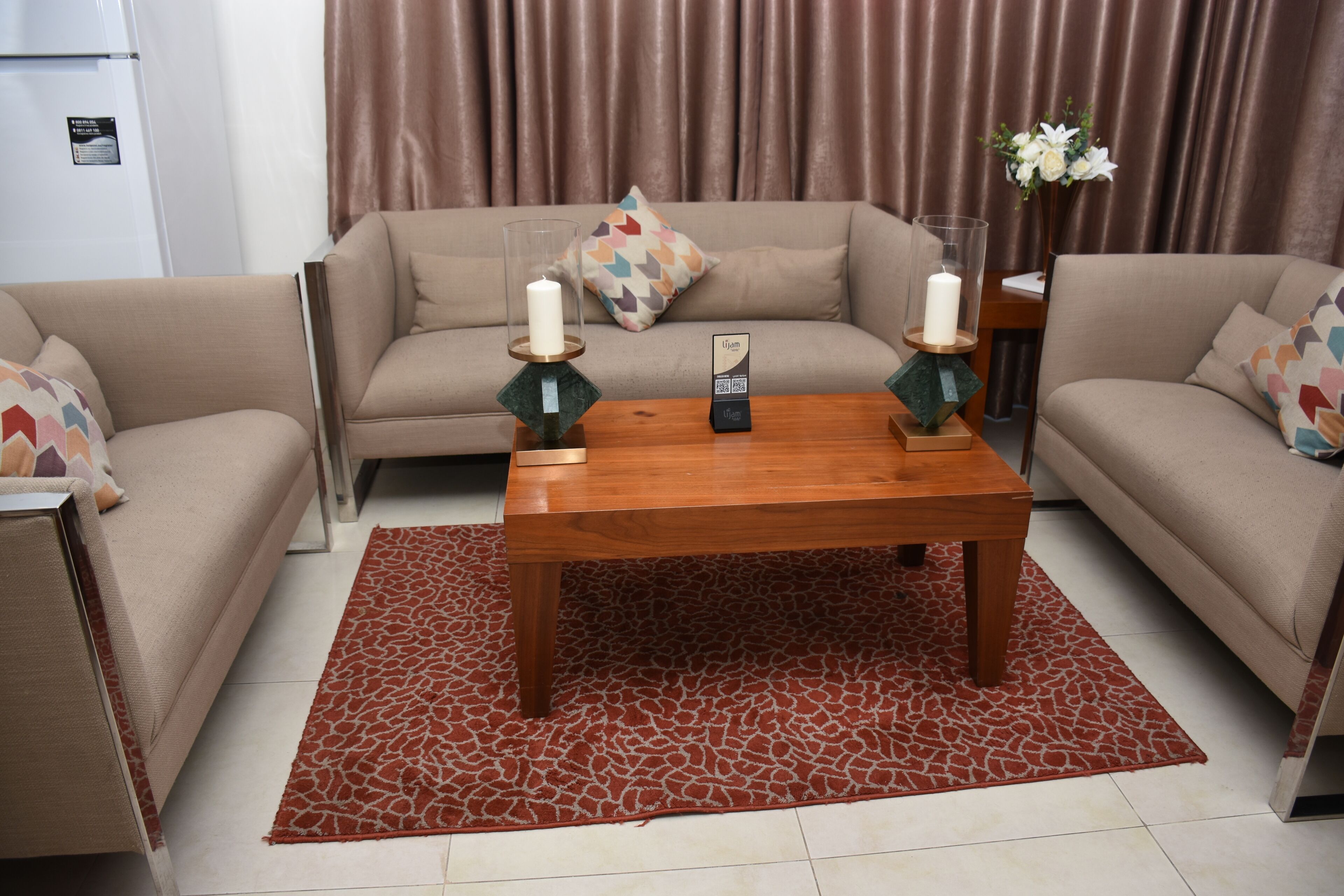 Una sala de estar con un sofá color beige, una mesa de centro de madera y una alfombra roja estampada.