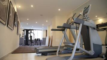 Une salle de sport à domicile équipée de tapis de course, de vélos elliptiques et de matériel de musculation.