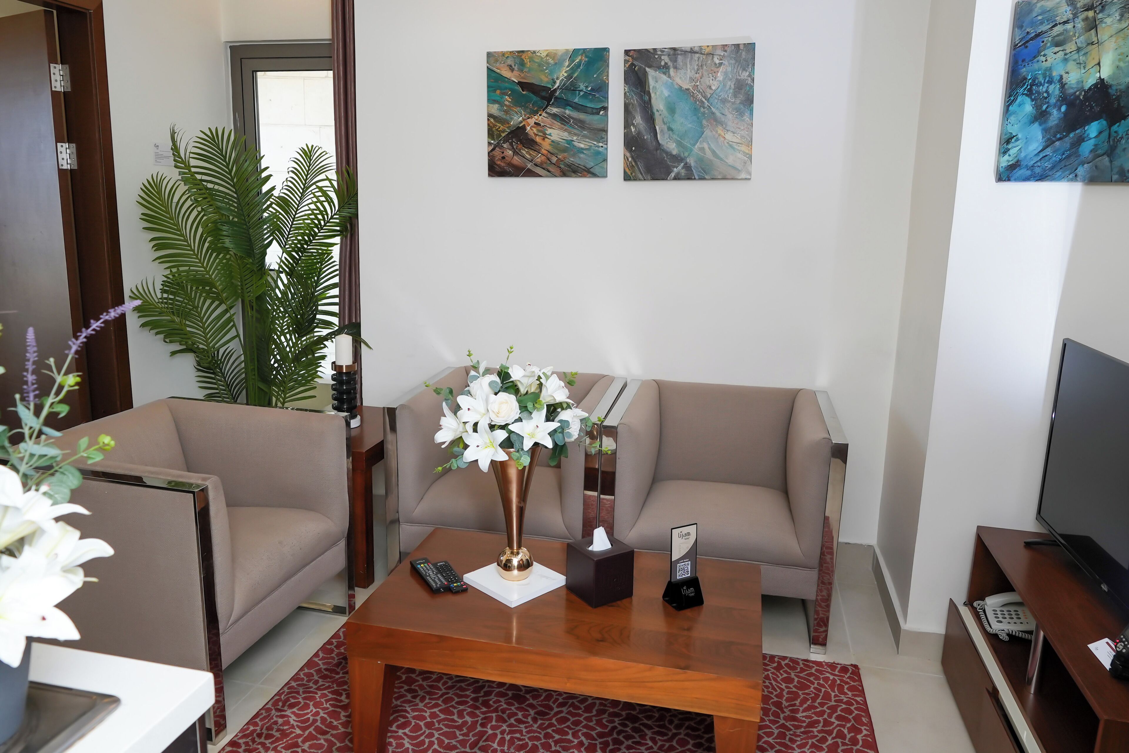 Una sala de estar con dos sofás, una mesa de centro con un florero y un televisor de pantalla plana, además de obras de arte en la pared.