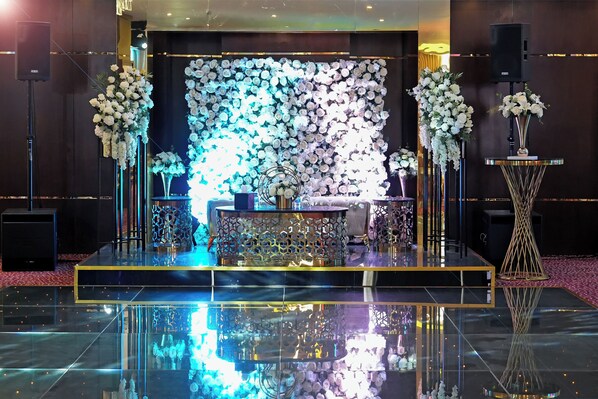 Un escenario con un fondo floral, un atril y dos oradores.